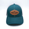 Front view of teal LoPro Trucker Cap with Slave Free - Eco Friendly - Innovative wordingbrown leather patch.  Fair Flies logo