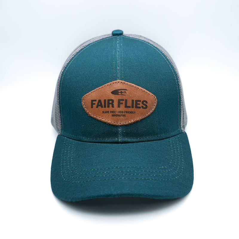 Front view of teal LoPro Trucker Cap with Slave Free - Eco Friendly - Innovative wordingbrown leather patch.  Fair Flies logo